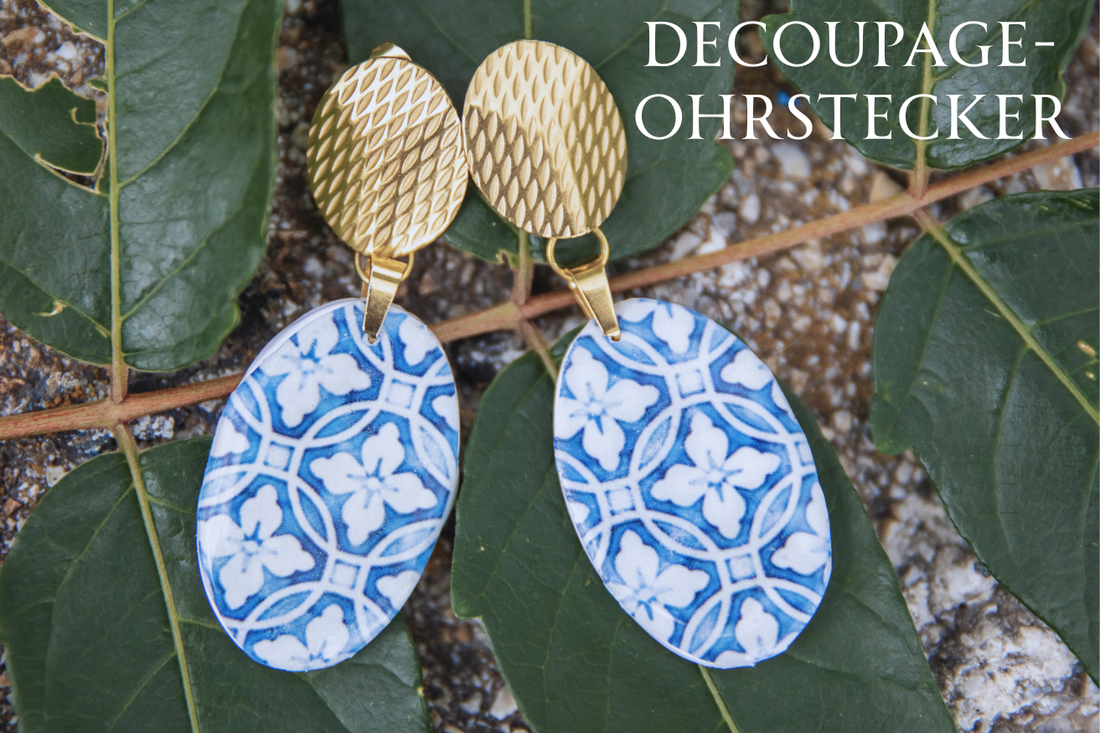 Nahaufnahme eines handgemachten Ohrrings aus weißem Polymer Clay, blau-weißem Decoupagepapier und UV-Resin.