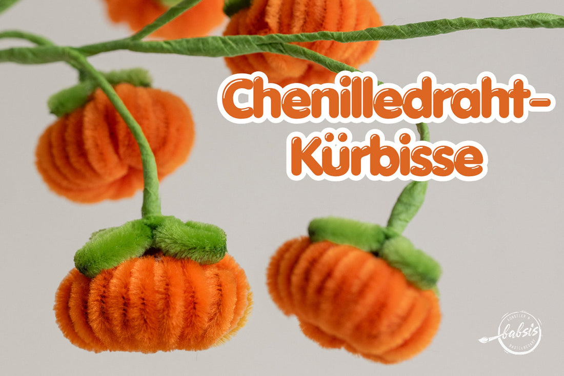 Orange Kürbisse mit grünen Blättern an umwickelten Drahtstielen und dem Schriftzug „Chenilledraht-Kürbisse“.