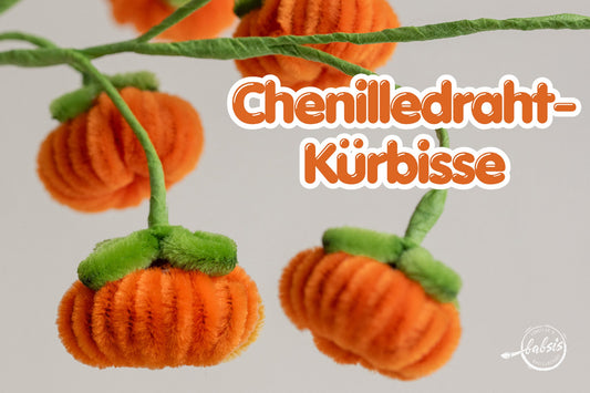 Orange Kürbisse mit grünen Blättern an umwickelten Drahtstielen und dem Schriftzug „Chenilledraht-Kürbisse“.